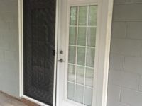 A white door with a screen door on a porch.