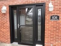 A black door is on a red brick building.