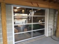 A garage door with a lot of windows is sitting on top of a brick wall.