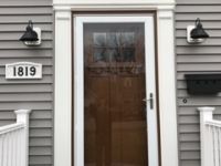The front door of a house with a white trim and a brown door.