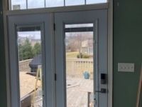 A room with a door and a window with a view of a deck.