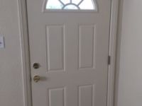 A white door with a stained glass window in a hallway.