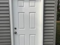 A white door is sitting on the side of a building.