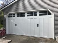 A white garage door is sitting on the side of a house.
