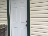 A white door with a green trim is on the side of a house.