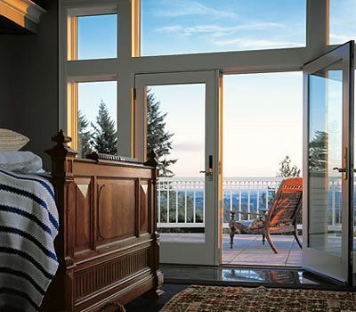 A bedroom with a bed and a balcony with a view of the ocean