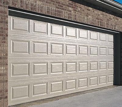 A white garage door is open on a brick building.