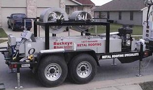 A trailer for buckeye metal roofing is parked in front of a house.