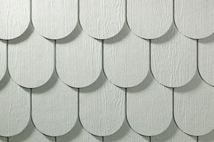 A close up of a white wooden wall with shingles on it.