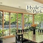 A dining room with a table and chairs and lots of windows.