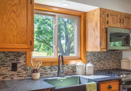 A kitchen with a sink , stove , microwave and window.