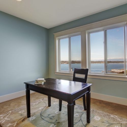 A desk and chair in a room with a view of the water