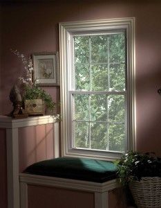 A room with a window and a bench with a green cushion.