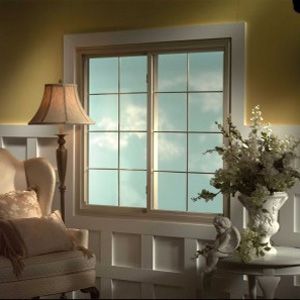 A living room with a chair a lamp and a vase of flowers