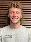 A man with curly hair and a beard is smiling for the camera.