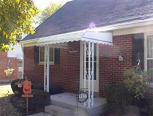 A brick house with a white awning on the porch.