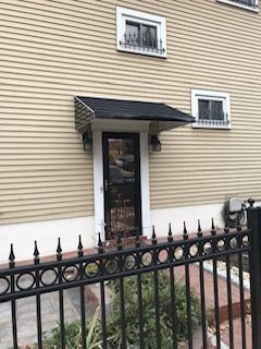 A house with a fence around it and a canopy over the door.