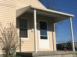 A small house with a porch and a white door.