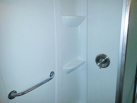 A shower stall with a hand rail and a shower head.