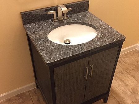 A bathroom sink with a granite counter top and a faucet.