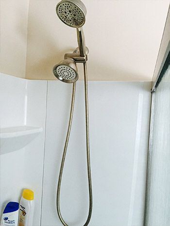 A shower head is hanging from the ceiling in a bathroom.