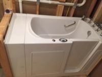 A walk in tub with a door in a bathroom.