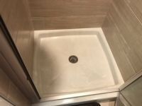 A shower stall with a drain in a bathroom.