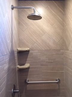 A shower with a shower head and a hand rail.