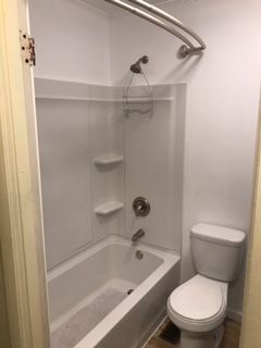 A bathroom with a tub , toilet and shower.