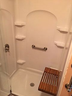 There is a wooden bench in the shower.