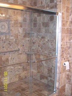 A bathroom with a sliding glass shower door and a toilet paper holder