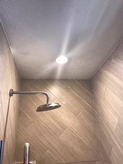 A shower head is hanging from the ceiling in a bathroom.