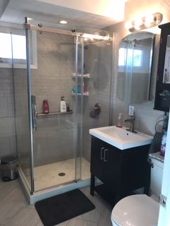 A bathroom with a sink , toilet , shower and mirror.