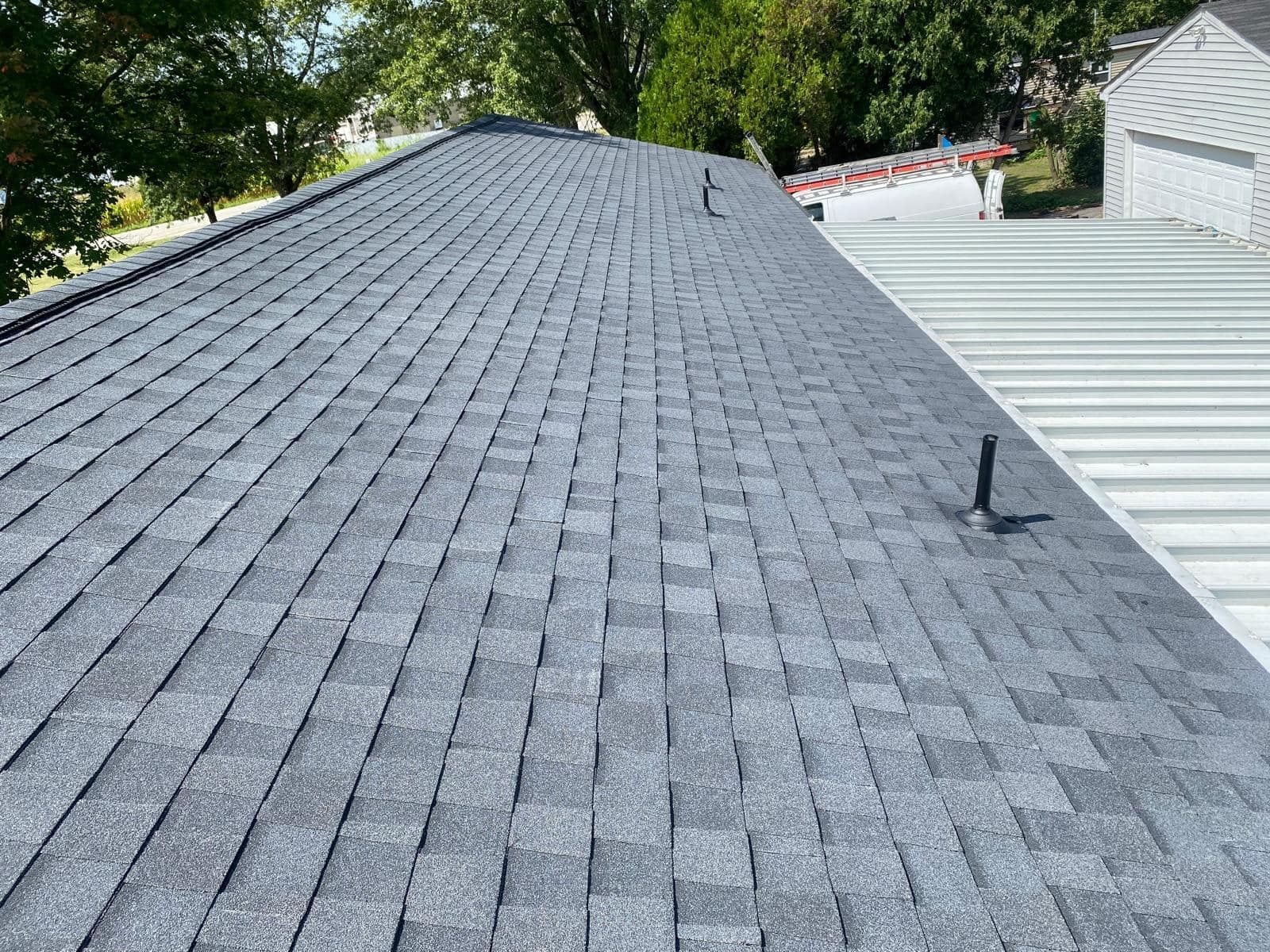 The roof of a house with a gray shingle roof and a metal roof.