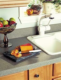 A kitchen counter with a sink and a bowl of fruit