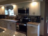A kitchen with white cabinets , stainless steel appliances , granite counter tops and a stove.