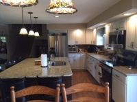 A kitchen with white cabinets , granite counter tops , stainless steel appliances and a large island.