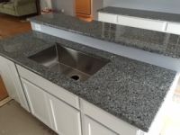 A kitchen with granite counter tops and a stainless steel sink.