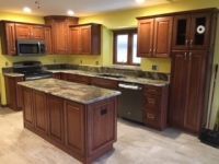 A kitchen with wooden cabinets , granite counter tops , stainless steel appliances and a large island.