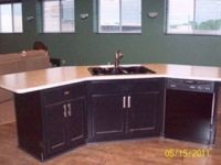 A kitchen with black cabinets , a sink , and a dishwasher.