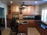 A kitchen with wooden cabinets , granite counter tops , and a ceiling fan.
