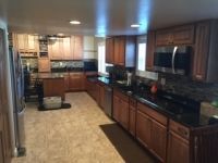 A kitchen with wooden cabinets , granite counter tops , and stainless steel appliances.