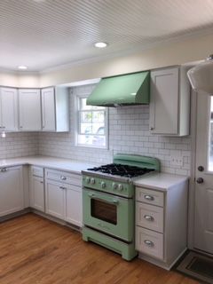 A kitchen with a green stove and white cabinets.