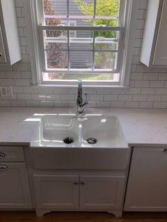 A kitchen with a sink, cabinets, and a window.