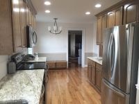 A kitchen with stainless steel appliances , wooden cabinets , granite counter tops and hardwood floors.