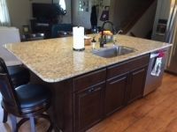 A kitchen with a large island with a sink and a chair.
