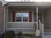 A house with a porch and a window with red shutters.