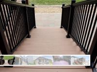 A wooden walkway with a black railing leading to a house.