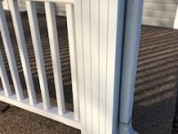 A white railing is sitting on top of a carpeted floor.