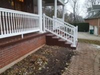 There is a white railing on the porch of a house.